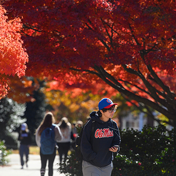 student walking through fall foliage