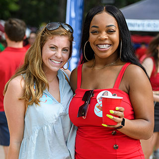 Two Ole Miss fans smile and pose as they tailgate in the Grove prior to a home football game.