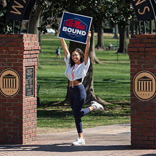 A prospective student poses for a photo under the Walk of Champions sign on the Ole Miss Oxford campus