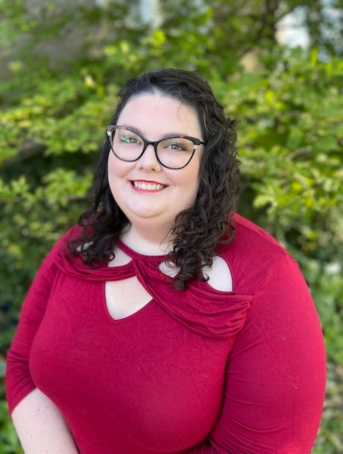 Headshot of Chelsea in a red dress standing in front of trees 