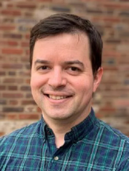 photo of smiling person in front of brick wall