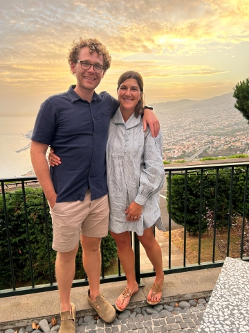 image of Sarah and her husband facing the camera with the ocean in the background