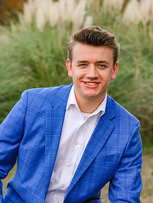 person outdoors in blue jacket smiling directly at the camera