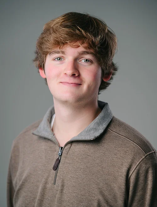 person smiling at camera; gray background