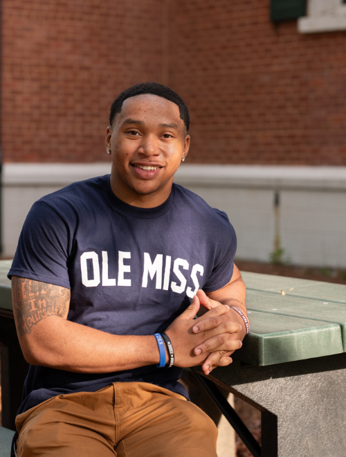 Duke Adams sitting outside at a park bench on the Ole Miss Campus. 
