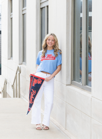 Josie standing outside the library with a rebels penant in her hand. 