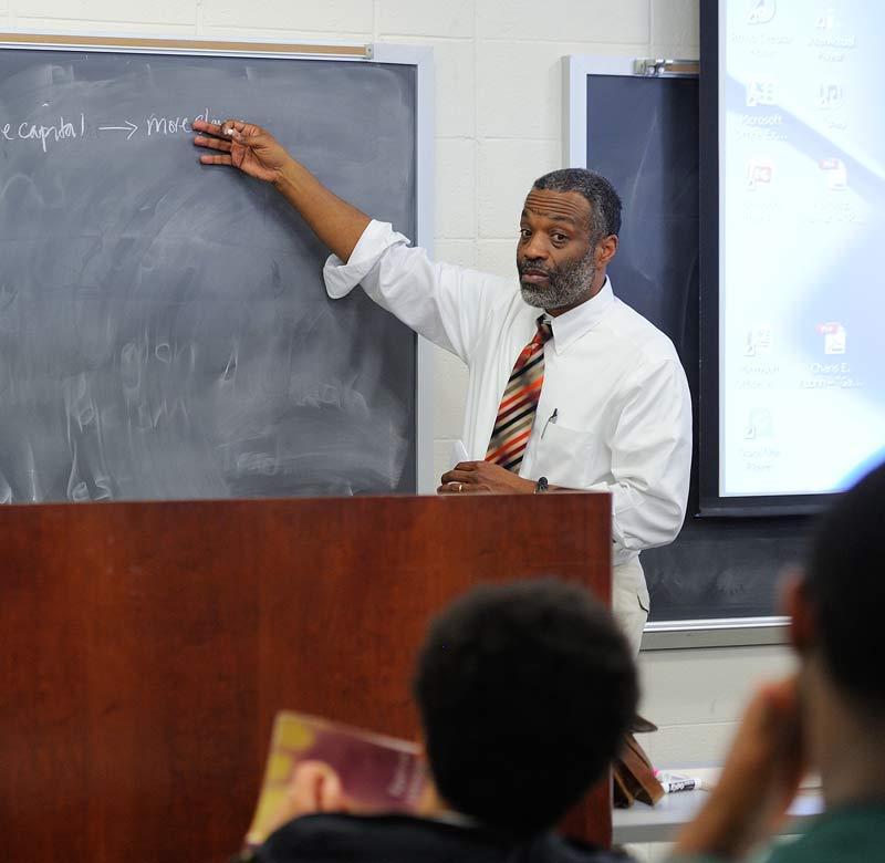 professor teaching to students around a table