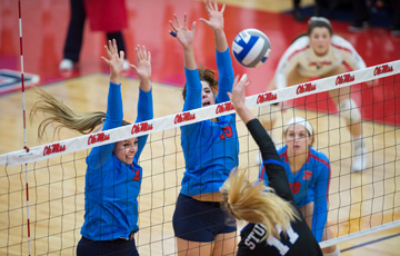 Volleyball match at the Gillom Athletics Performance Center. Four players at the net; two players jumping up to block the ball.