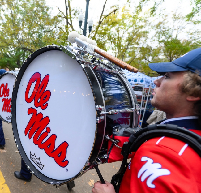 An Ole Miss band member marches through the Grove with their bass drum