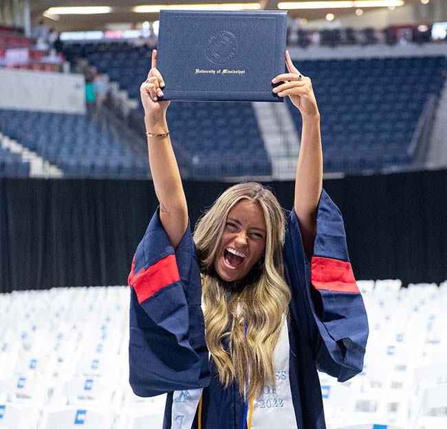 A recent Ole Miss graduate lifts her diploma and gives a celebratory Hotty Toddy after ceremonies at The Pavilion.