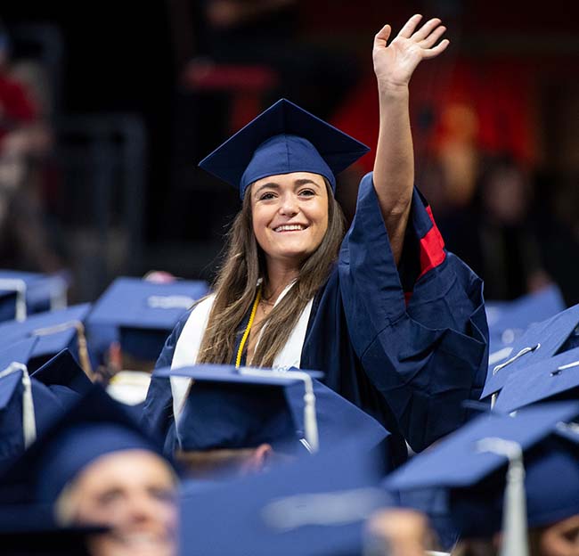 A new Ole Miss graduate waves to her family during a commencement ceremony in The Pavilion.