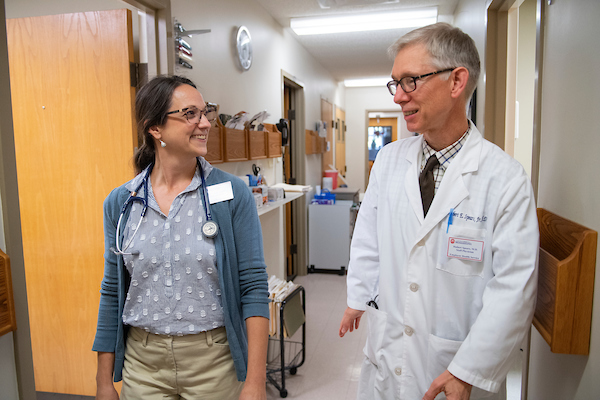 Two doctors talk in the halls of the student health center. 