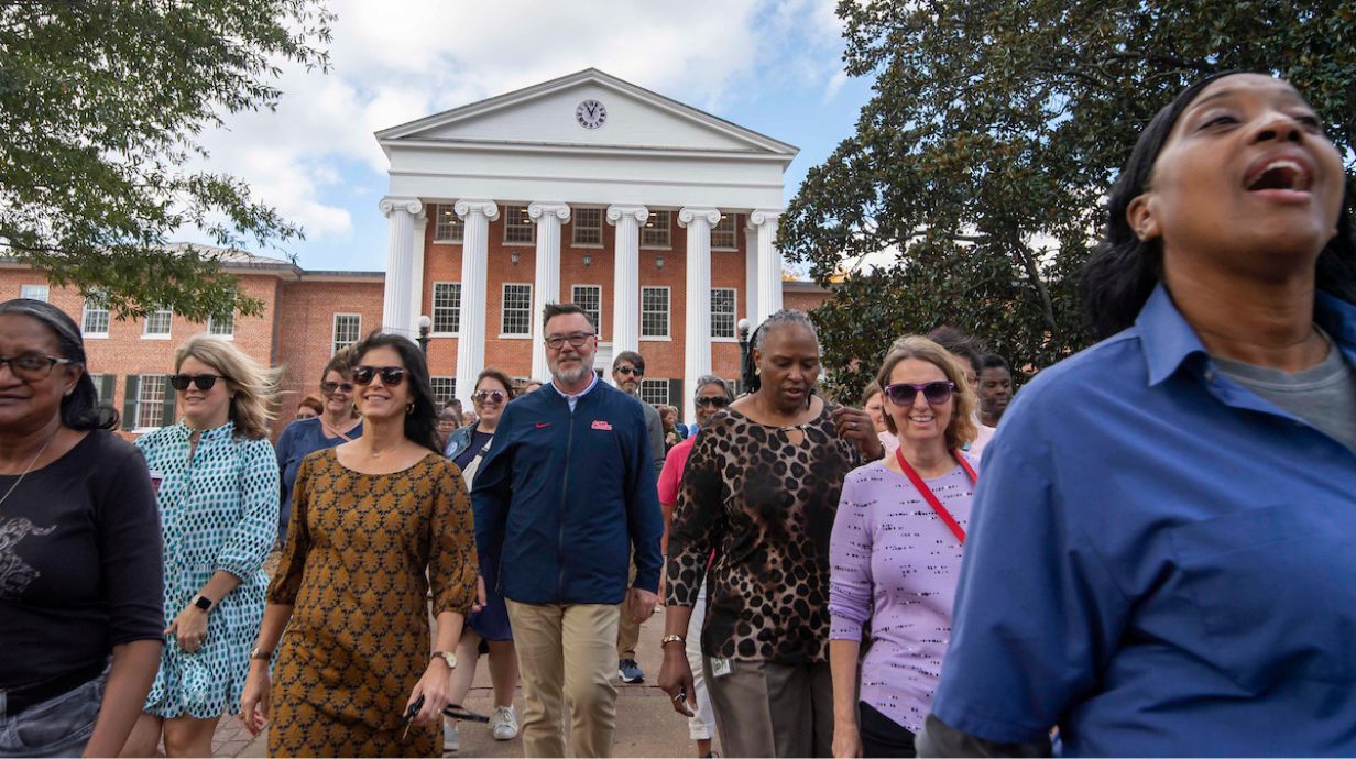 Faculty and staff walk in front of the Lyceum. 