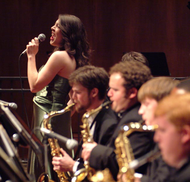 Person singing with brass band in foreground