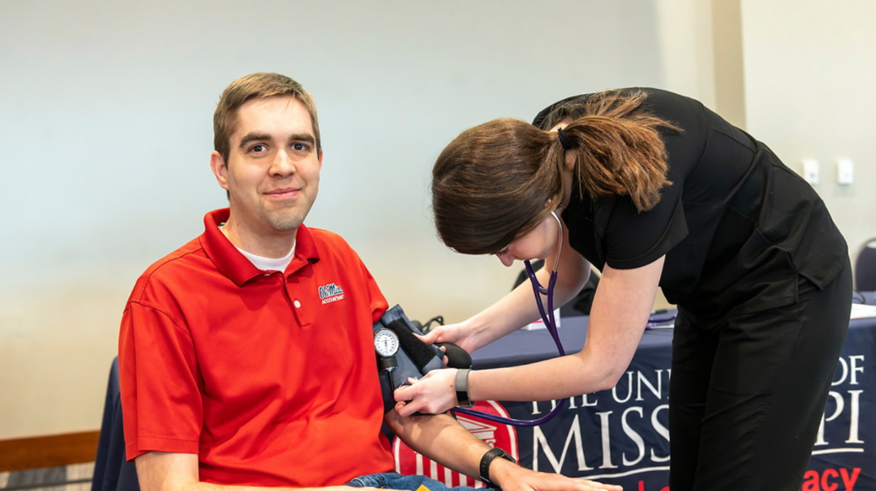 University staff member getting a blood pressure check at the Red, Blue and Well Spring Wellness Expo