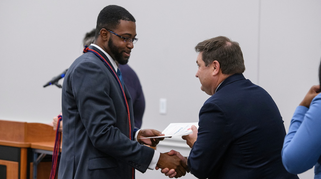 An employee is congratulated at the Red and Blue Graduation