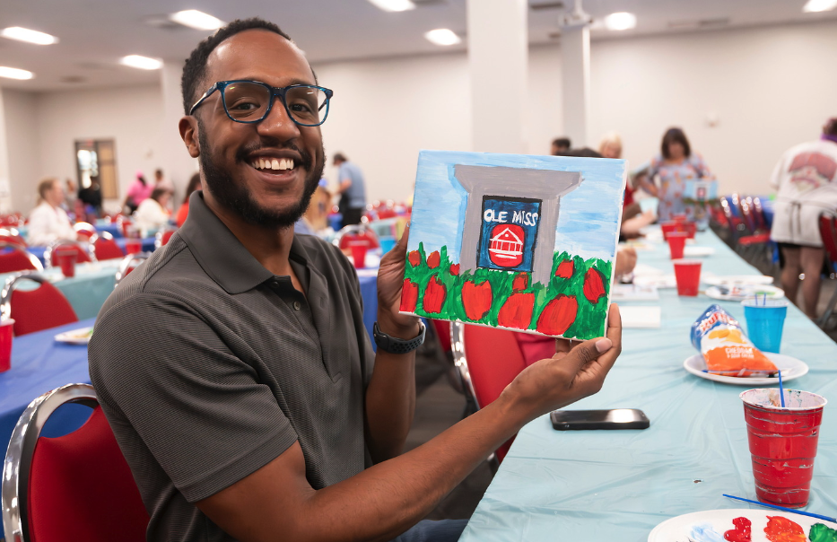 University team member painting at appreciate day event.