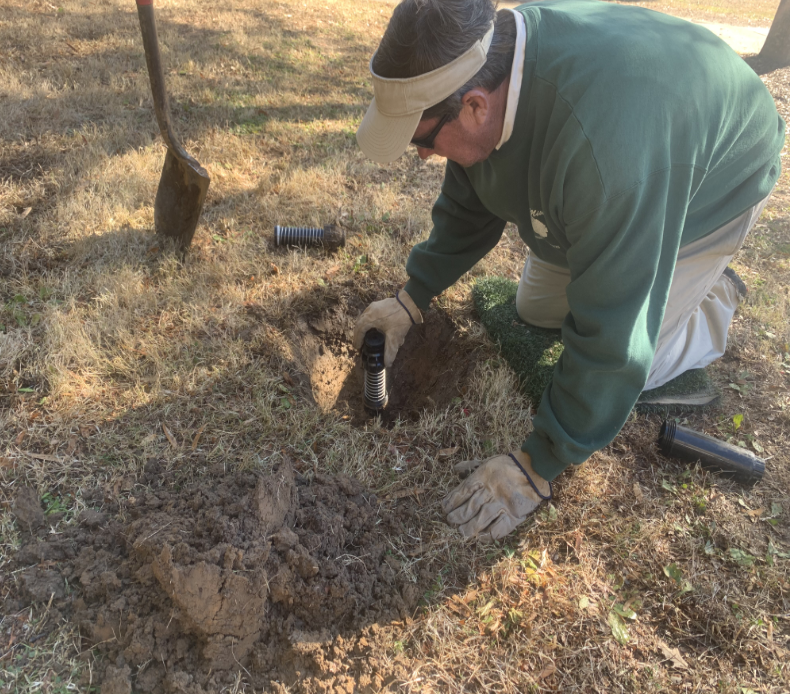 Irrigation tech installing sprinkler