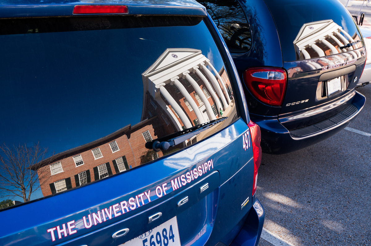 Two University vans with the Lyceum reflecting on the back windshield