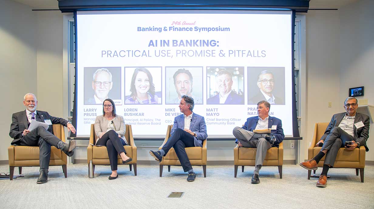 Five panelists on stage during the 2025 symposium.