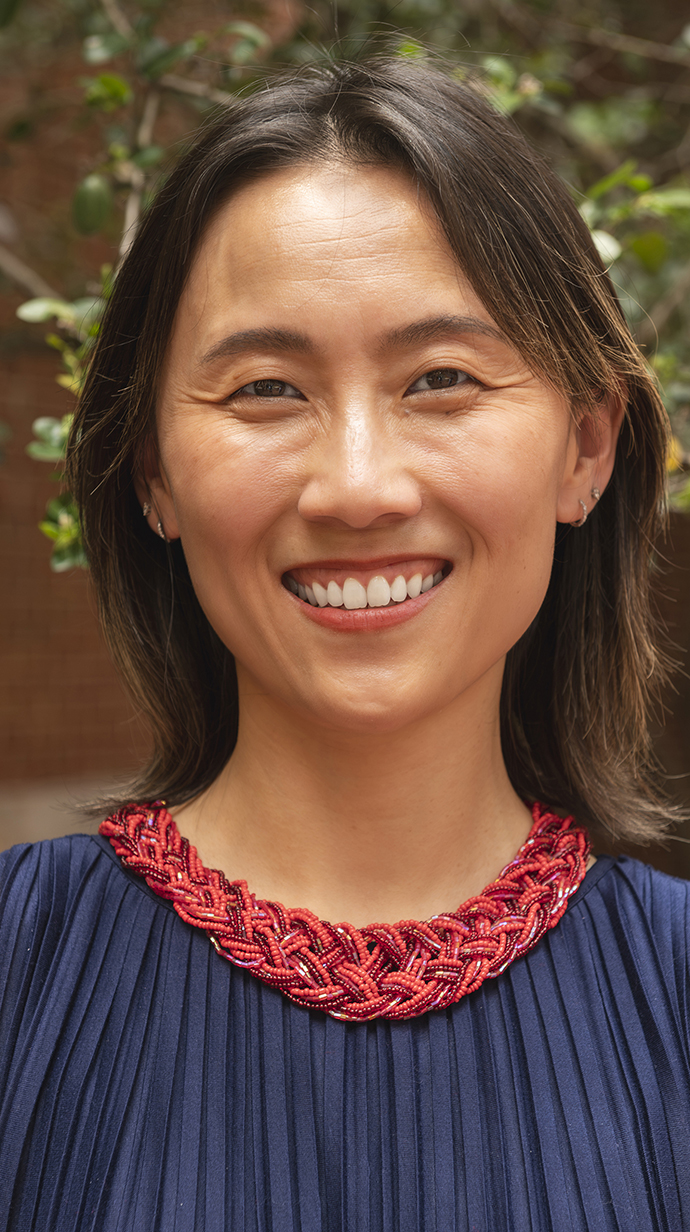 Headshot of a woman wearing a blue dress with a red woven neckline.