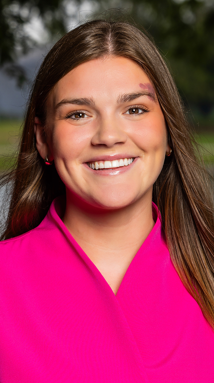Headshot of a woman wearing a hot pink blouse.