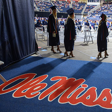 Graduates wait for their named to be called in the portico of the Tad Smith Coliseum during Commencement