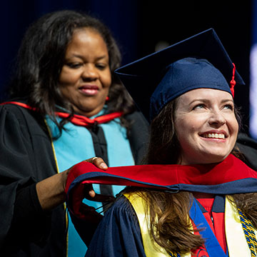 A recent graduate receives her hood from a faculty/staff member at the University of Mississippi