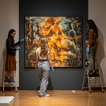Students and staff members install artwork at the University Museum