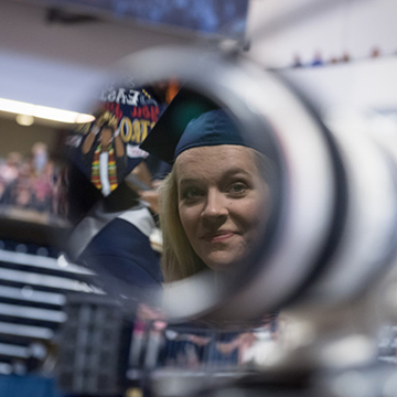 A graduate peers into the lens of a camera