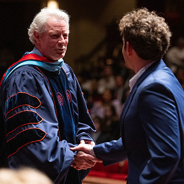 Chancellor Boyce greets a student with a handshake during Commencement exercises