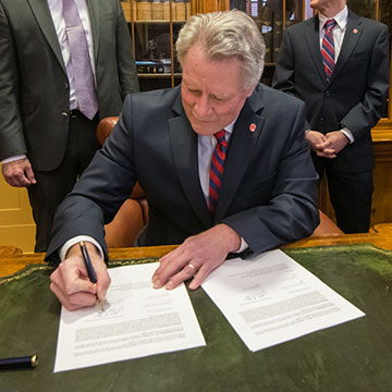 Chancellor Glenn Boyce signs a document inside the formal office of the Lyceum administration building