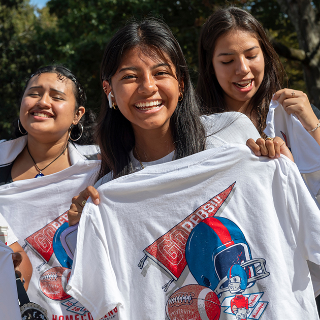 Students posing with rebel football t-shirts. 