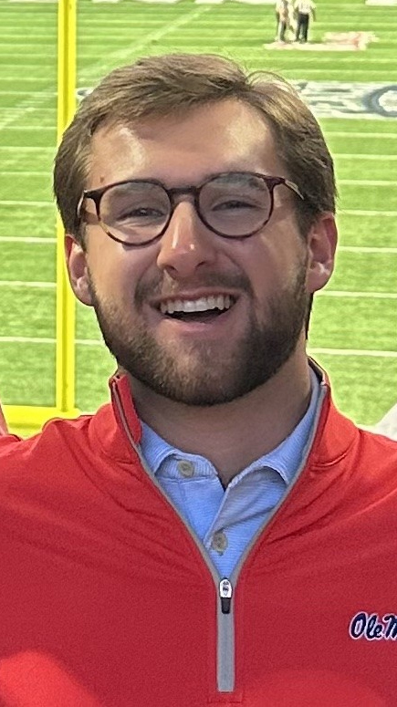 A young man years a red Ole Miss jacket over a blue polo shirt.
