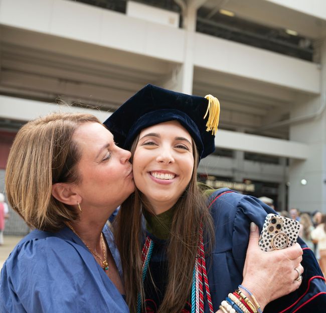 A graduate and family member celebrate together after graduation. 