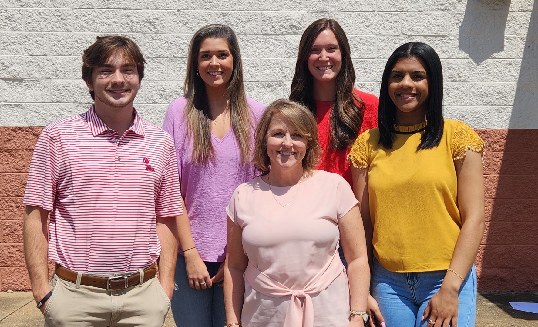 Five students pose in front of the CMSE logo.