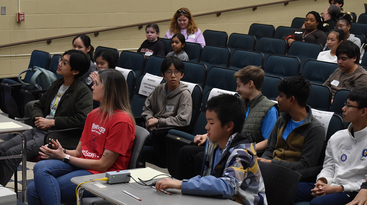A group of students seated in a school auditorium, participating in an Mathcounts contest.