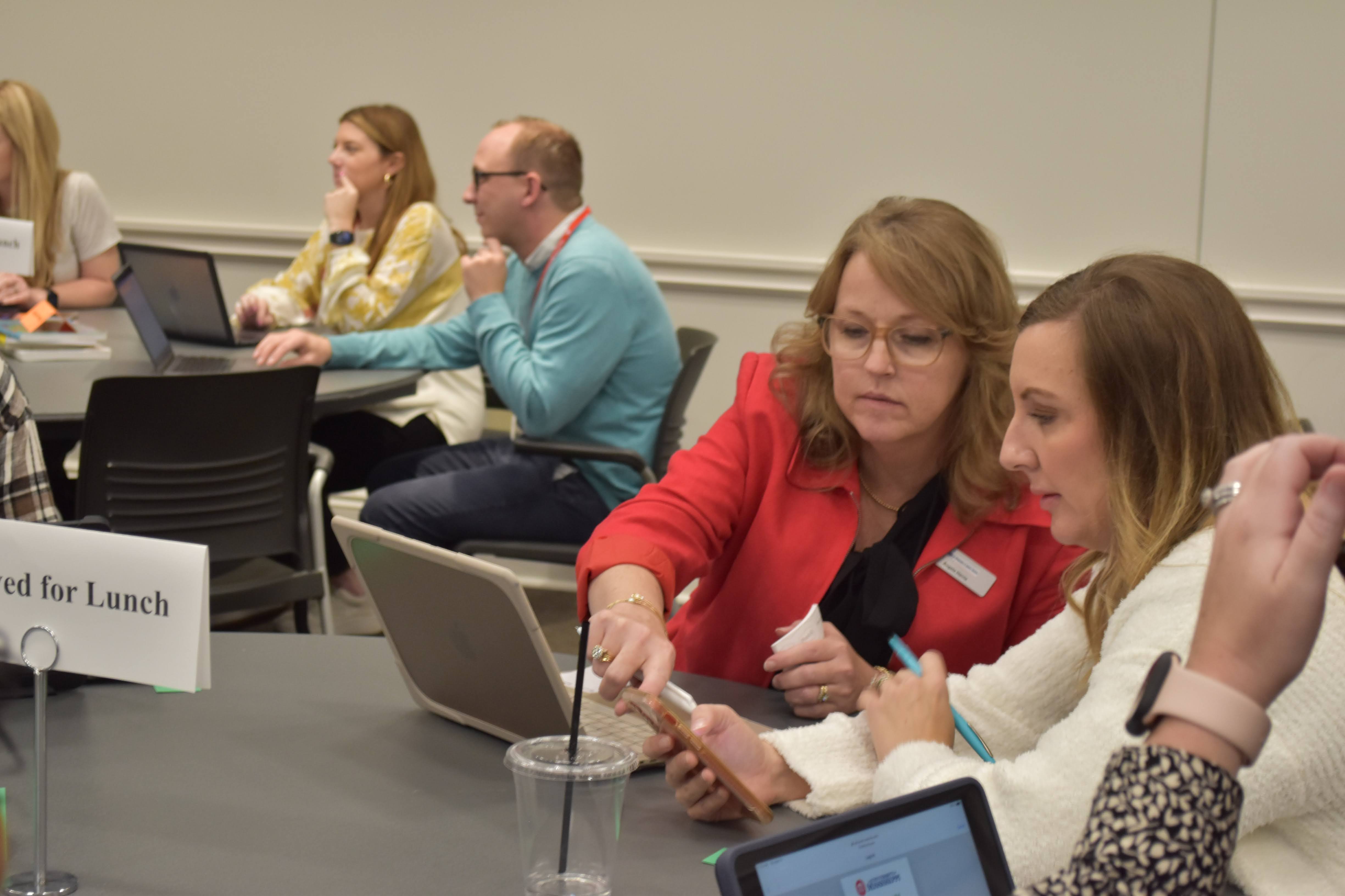 Two teachers discussing information on a computer screen.