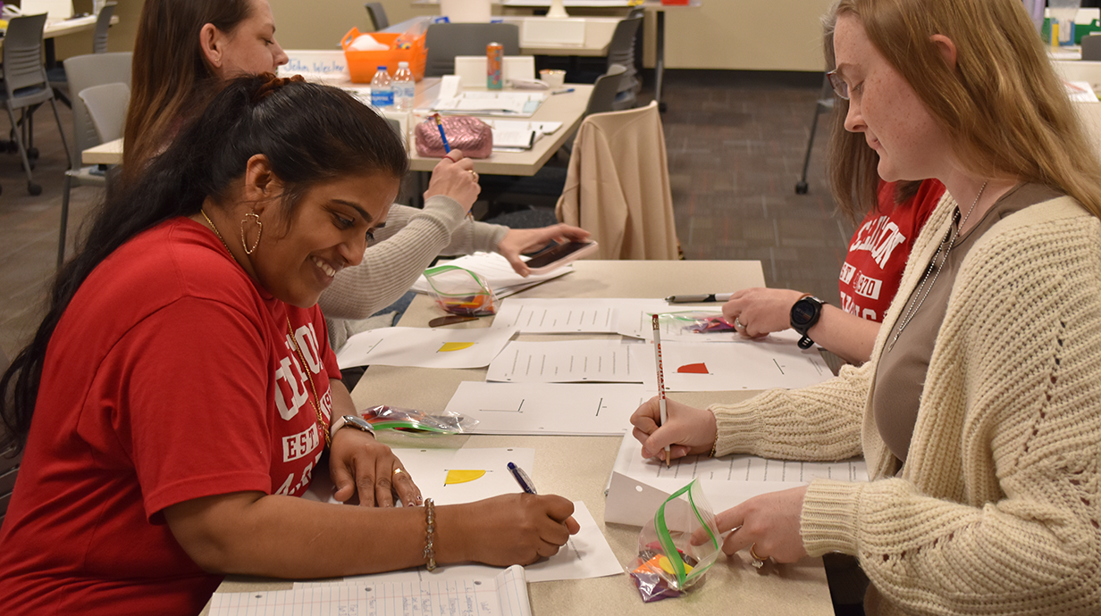 Teachers sitting at a classroom table, collaborating on a project.