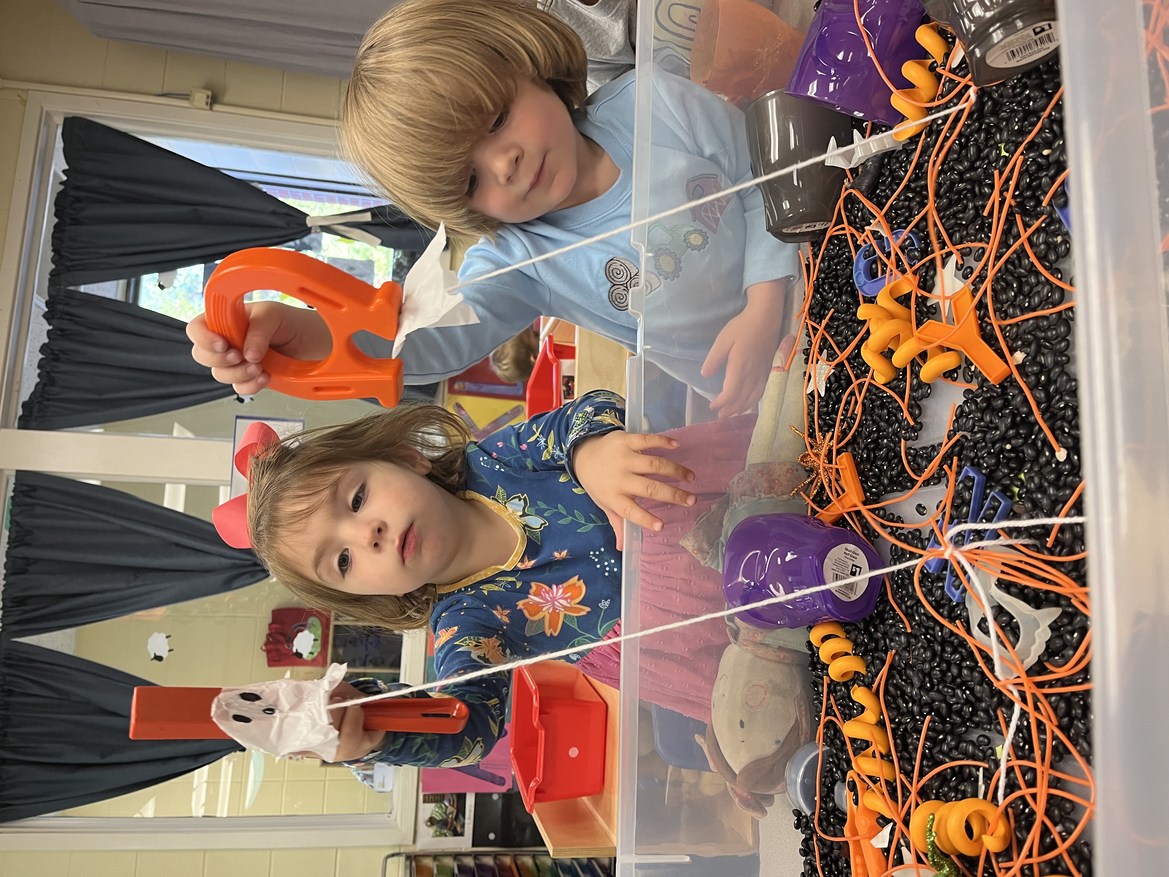 Two students play in a Halloween-themed sensory bucket. 