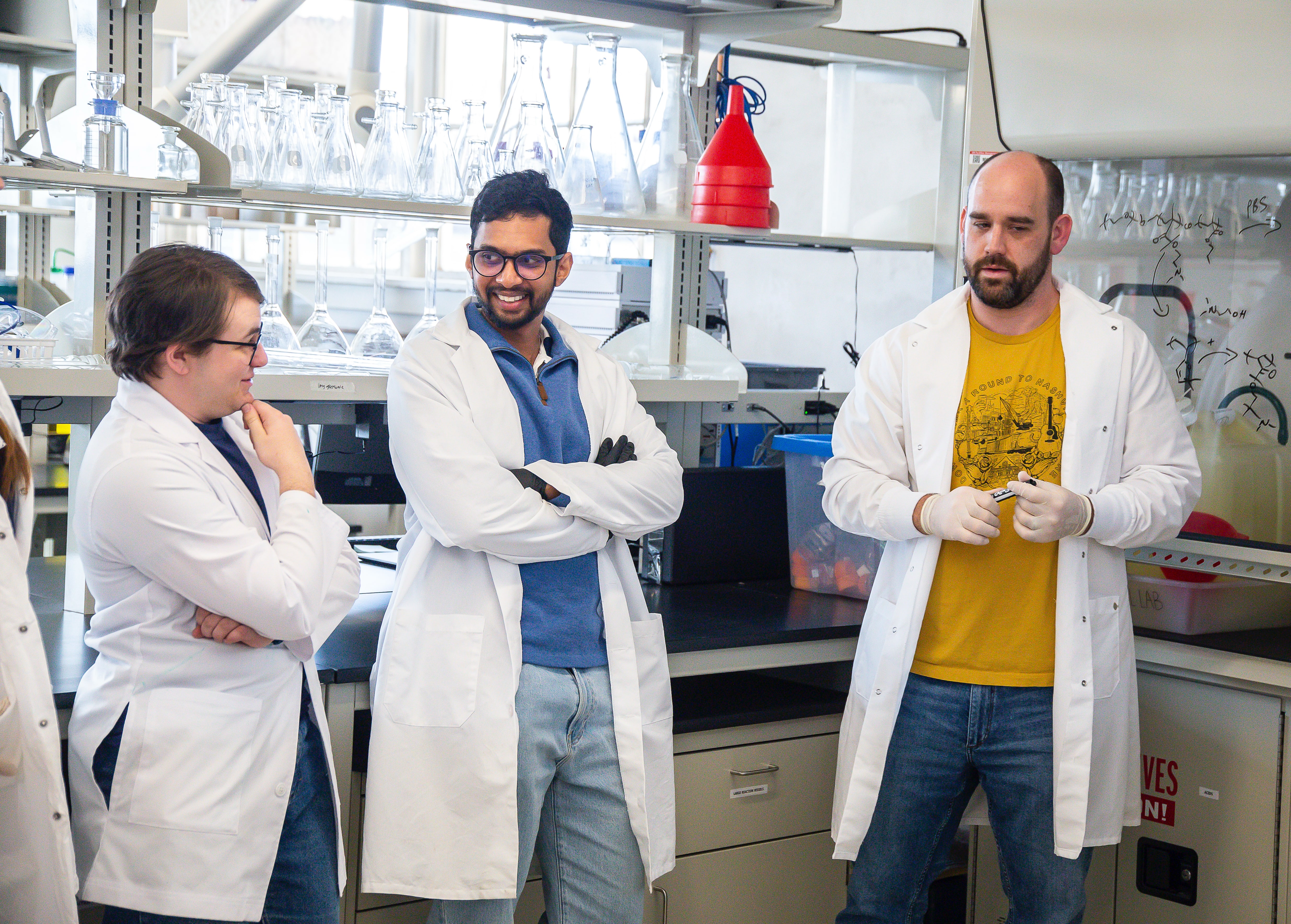A group of 3 biomedical researchers conversing in a lab
