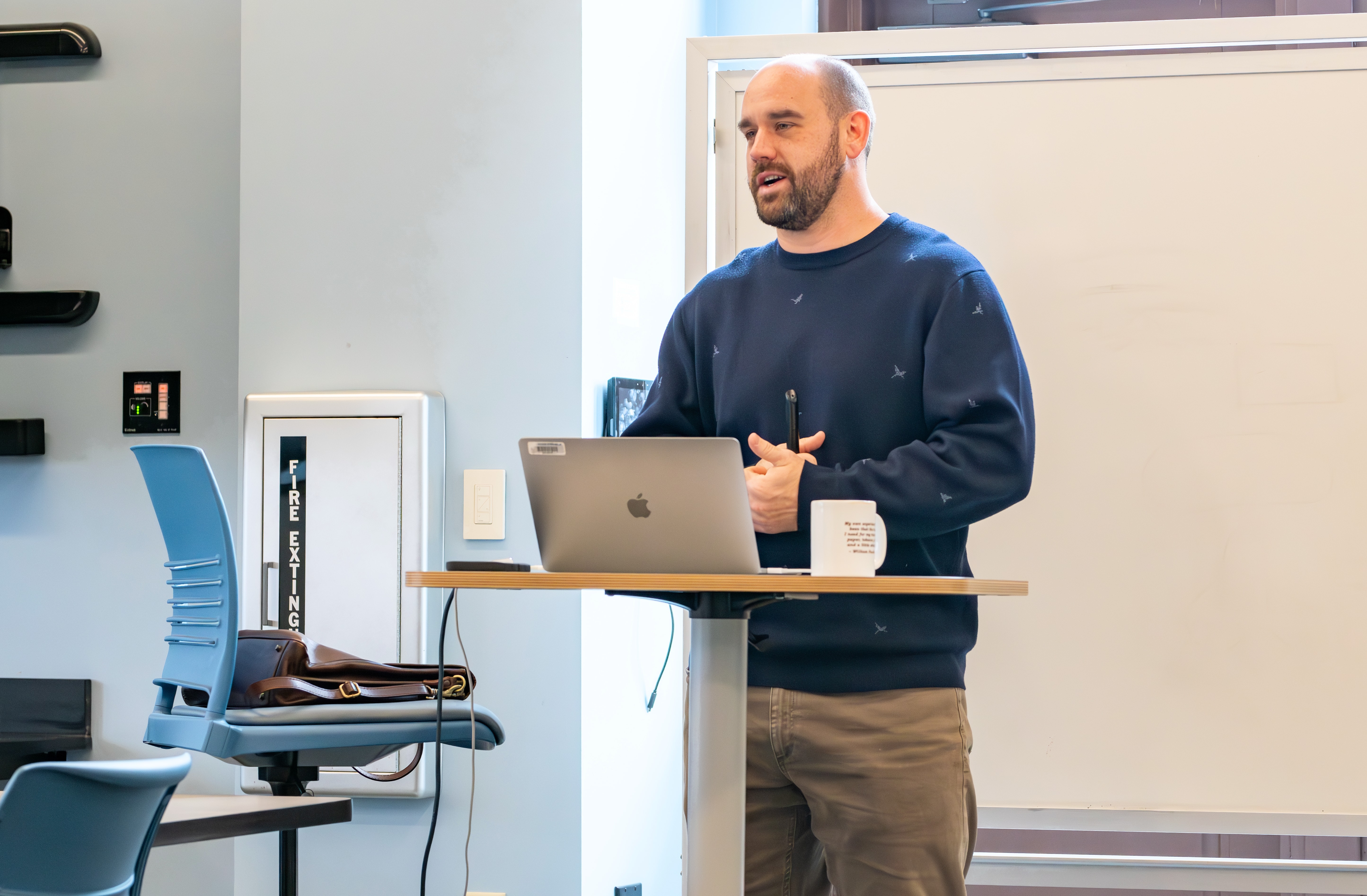 A biomedical professor stands mid-lecture at the front of a classroom.