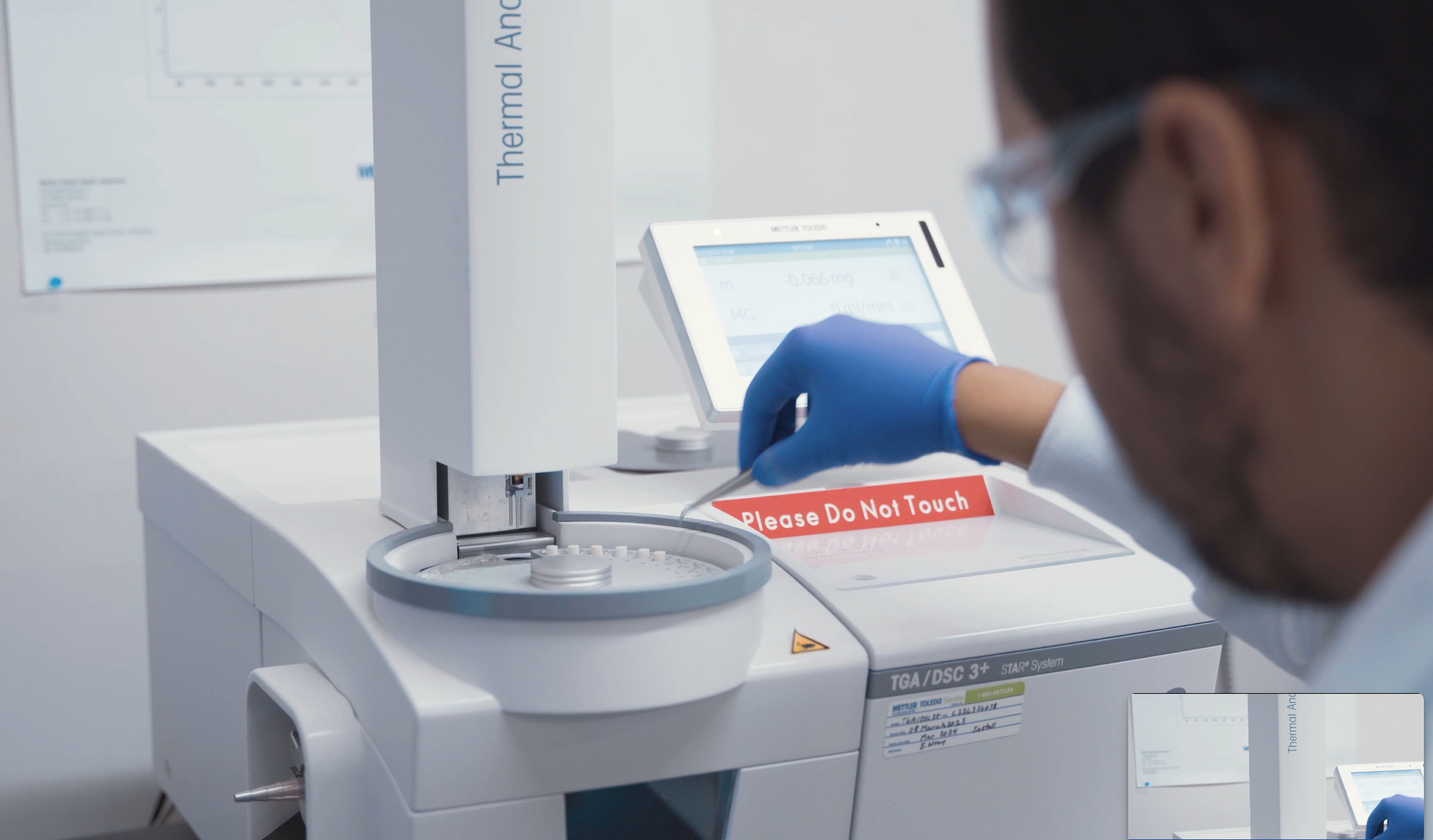 A researcher uses a pair of tweezers to place samples into a machine.