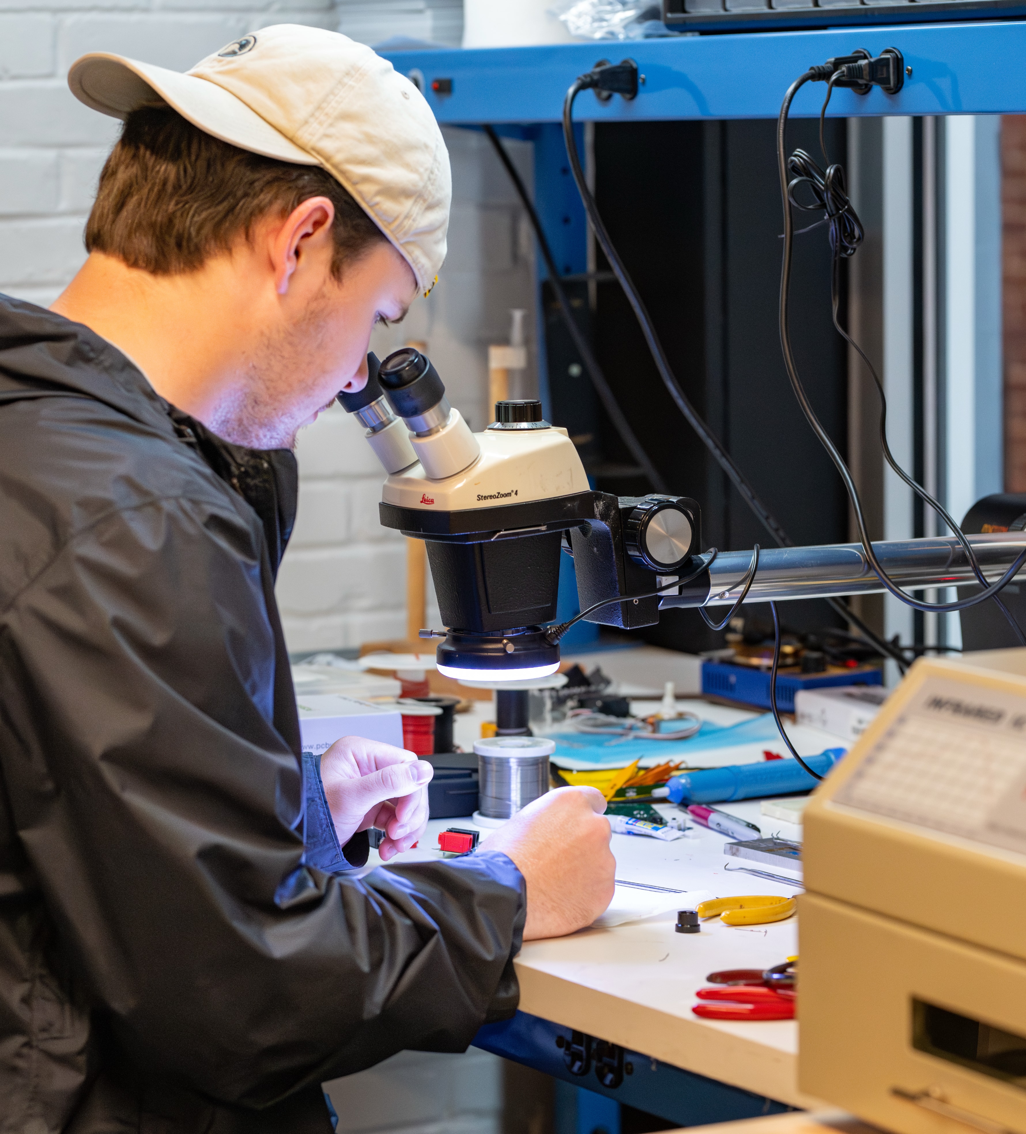 A student looks into a microscope to view electronic components