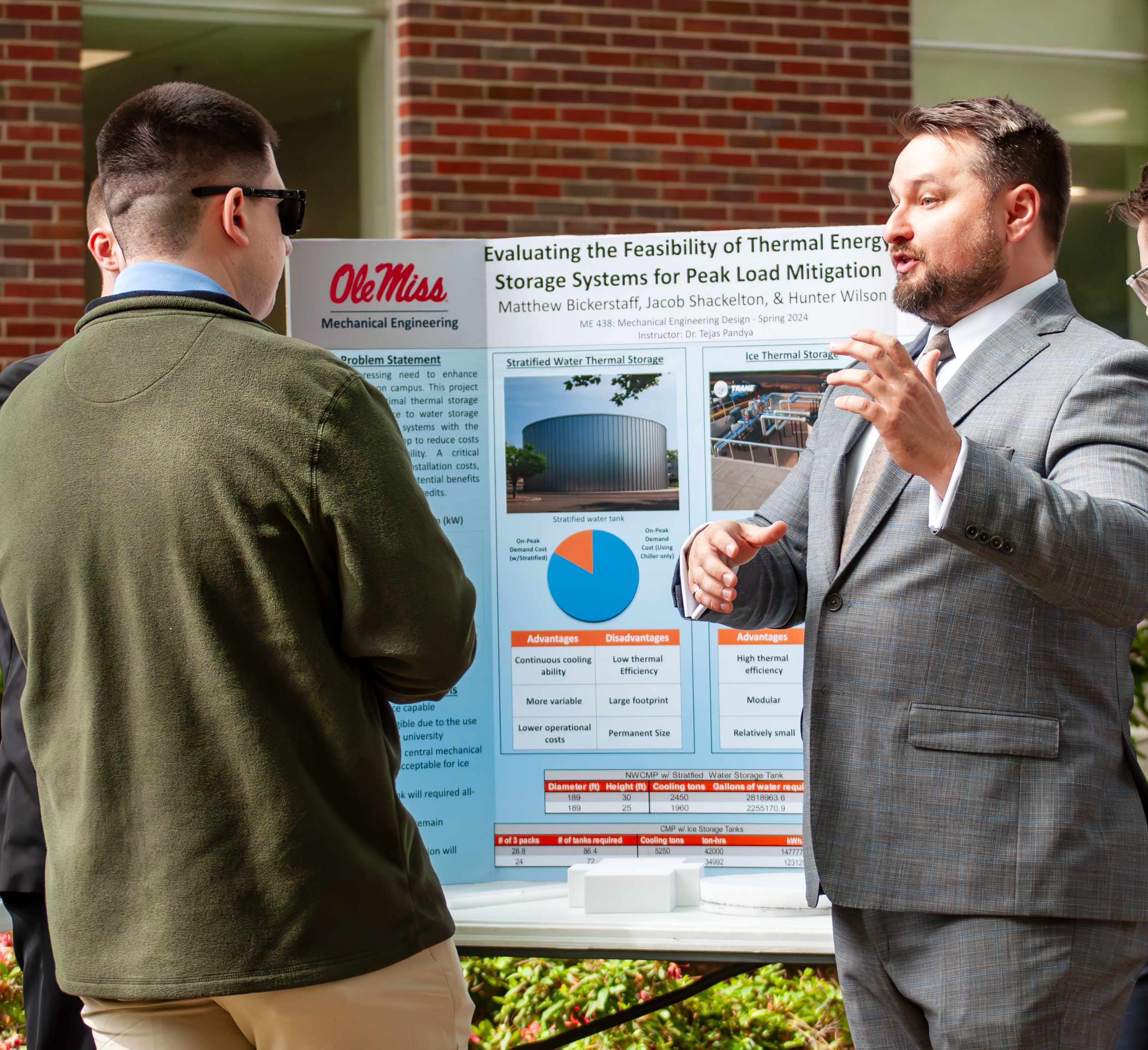 A student explains their mechanical engineering project at an event.