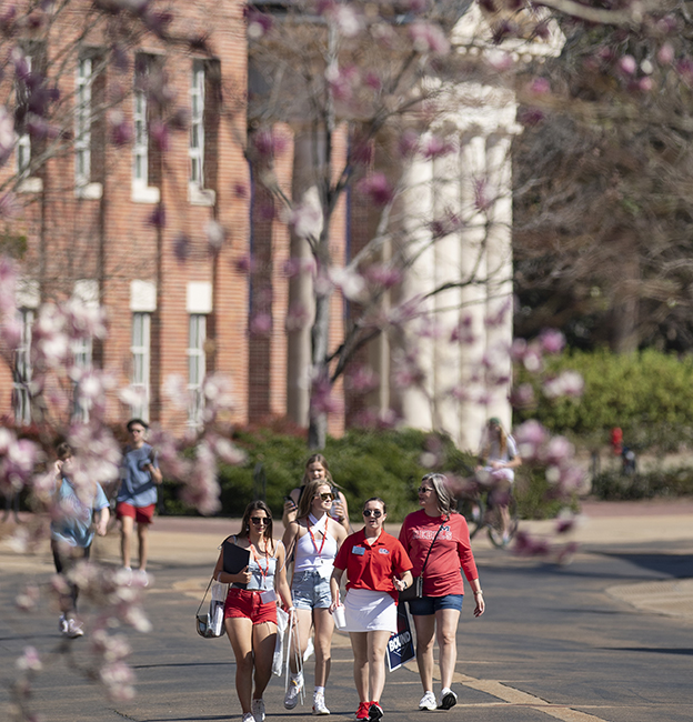 Incoming freshman visit campus with their friends and family for Admitted Student Day. They walk past the lyceum on Business Row with a tour guide.