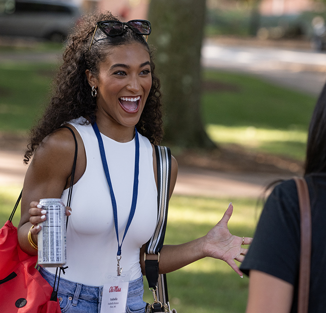 A student smiles and holds her hands out in excitement