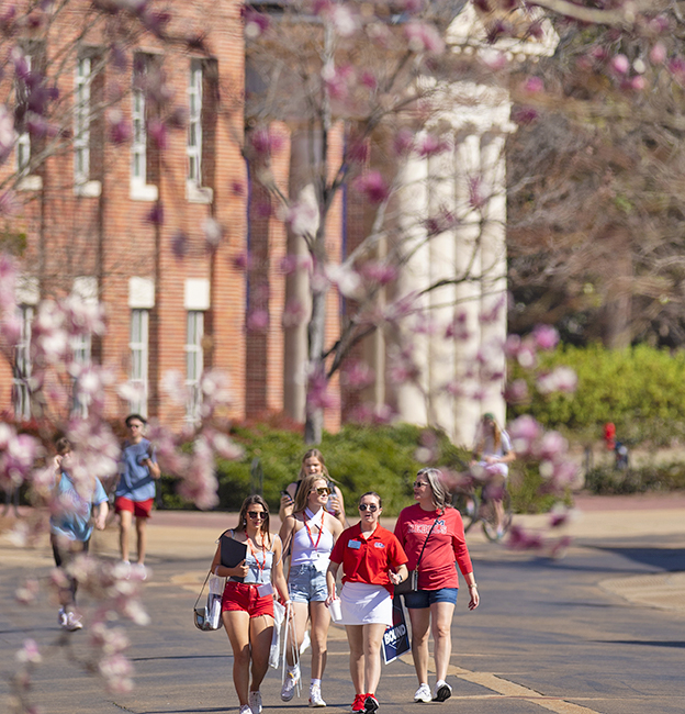 Incoming freshman visit campus with their friends and family for Admitted Student Day. They walk past the lyceum on Business Row with a tour guide.