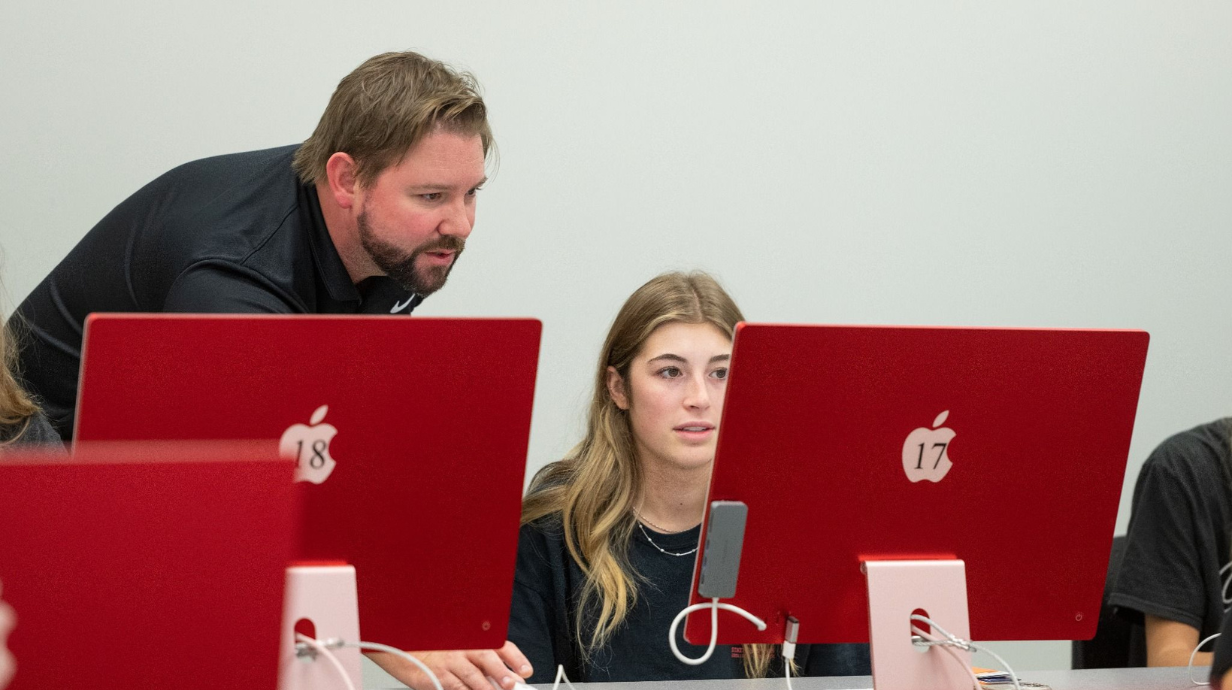 Professor helping a student access materials on their computer. 