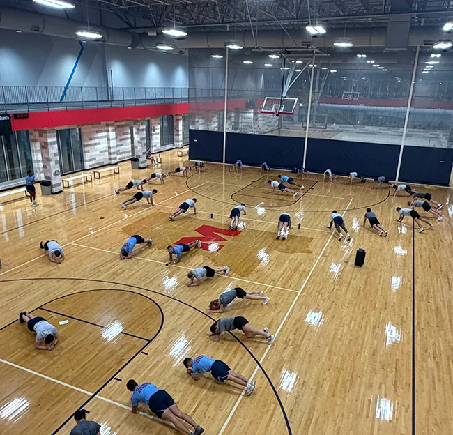 bird's eye view of large group of people doing planks on gym floor